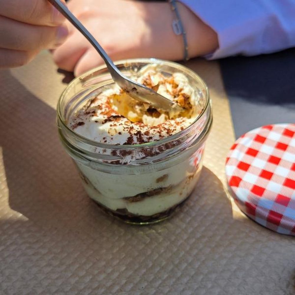 Un dessert en verrine servi avec une cuillère, près d'un couvercle à carreaux rouges