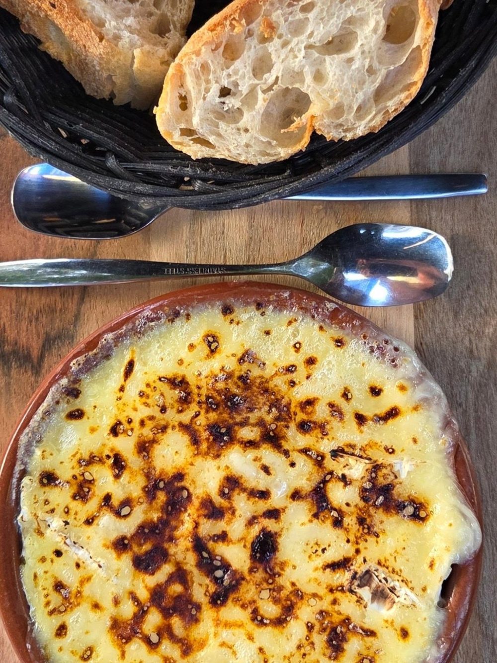 Un gratin doré servi dans un plat en fonte, avec du pain grillé